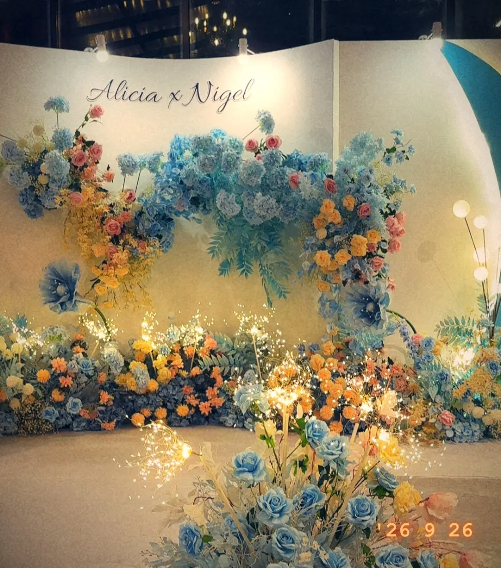 A floral wedding backdrop reading “Alicia x Nigel”